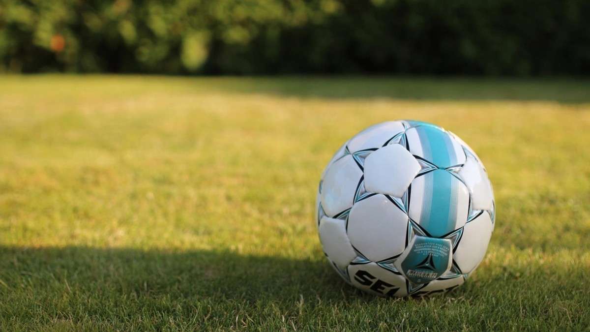 Soccer ball resting on a sunlit grass pitch
